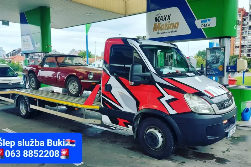 Crveni oldtajmer na platformi šlep vozila na benzinskoj pumpi